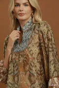 A woman wearing a loose, bohemian-style printed tunic top with a high mandarin collar. The top features a sage green and brown paisley pattern with a contrasting dusty blue patterned inner collar.
